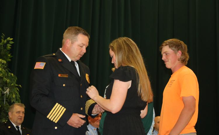 Lake City Fire Chief Josh Wehinger receives his badge from wife, Lari, as son, Ty, looks on during a swearing-in ceremony Tuesday night at the Columbia County School District Administrative Complex Auditorium. (TONY BRITT/Lake City Reporter)