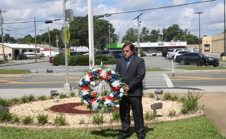 Chad Adams, the associate director for operations at the Lake City VA Medical Center, solemnly reflects after placing a wreath outside the facility Wednesday. (TONY BRITT/Lake City Reporter)