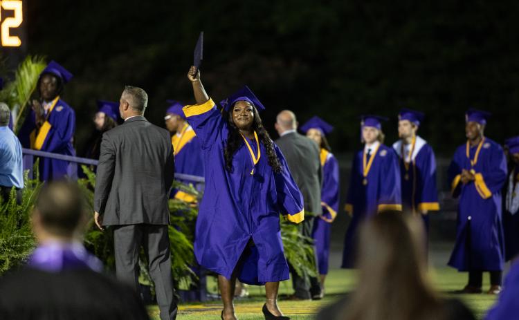 A graduate proudly holds up her diploma after walking off stage during commencement exercises Friday. (RAY CARPENTER/Special to the Reporter)