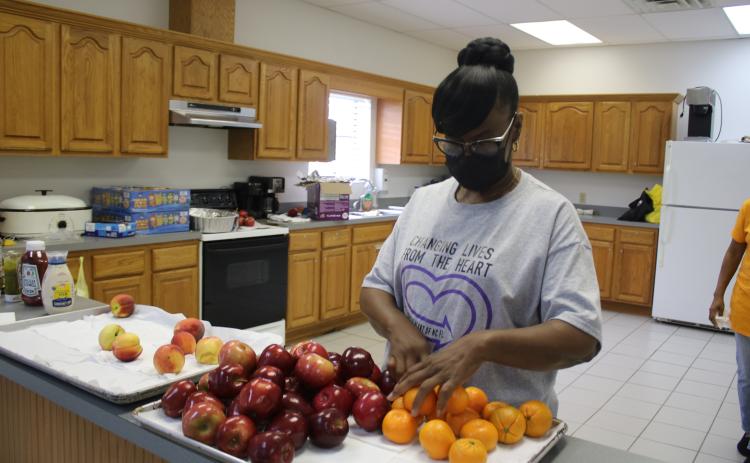 Essie Akins, a Straight From the Heart of North Florida committee member, arranges fruit during the organization’s inaugural community event on Saturday at the Fort White Community Center. (TONY BRITT/Lake City Reporter)