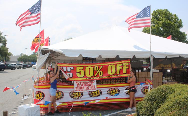 Kenzie Dungan (left), Columbia FFA senior president and her sister, Kaylan Dungan, Columbia FFA junior president, set up a banner outside the FFA fireworks stand Friday afternoon. (TONY BRITT/Lake City Reporter)