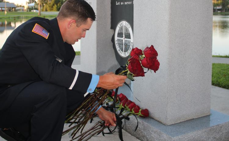 Austin Thomas, a Lake City Fire Department driver/engineer, lays roses on the Columbia County Public Safety Memorial on Tuesday in honor of fallen Columbia County public safety workers. (TONY BRITT/Lake City Reporter)