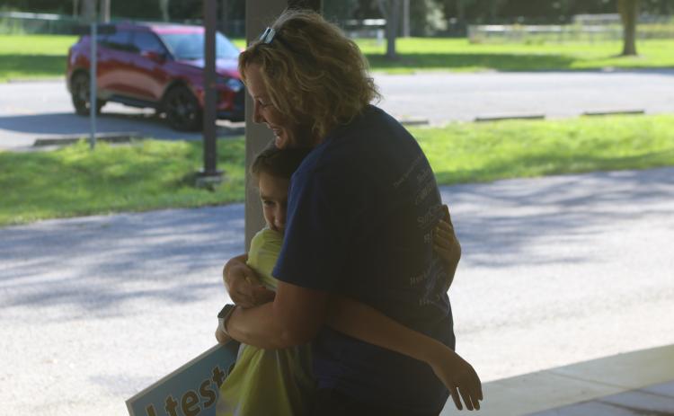 Dallas Douglass, 10, a fourth-grader at Columbia City Elementary School gets a hug from CCE third-grade teacher Jennifer Jordan on Monday afternoon. (TONY BRITT/Lake City Reporter)