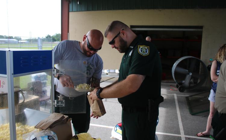 Columbia County Sheriff’s Office deputies Anthony Cortese and Mike Rodriguez bag up some popcorn at a ‘Summer Nights’ program last summer. (FILE)