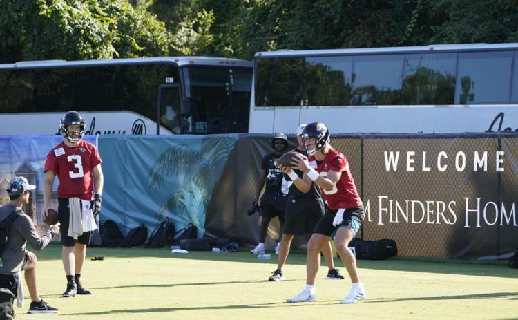 Jacksonville Jaguars quarterback Trevor Lawrence (right) takes a snap as quarterback C.J. Beathard (3) looks on during practice on Monday in Jacksonville. (JOHN RAOX/Associated Press)
