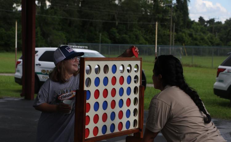 Keith Spence, 10, plays Connect Four with a Columbia County Sheriff’s Office school resource officer Friday during Summer Nights. (MORGAN MCMULLEN/Lake City Reporter)