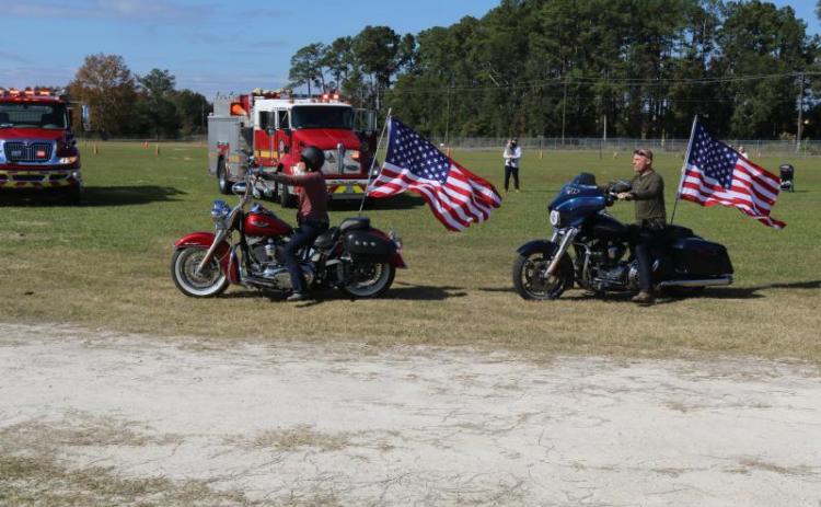 A pair of riders take off with American flags waving during the American Legion Riders’ 2019 Toys for Tots run. (FILE)