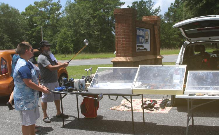 Prospective buyers take a closer look at a pair of golf clubs at Friday’s United Way of Suwannee Valley community yard sale. (TONY BRITT/Lake City Reporter)