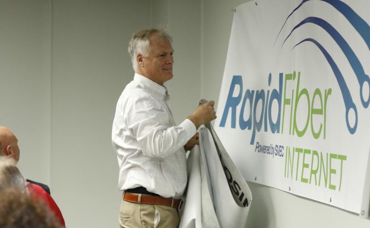 SVEC Communications Director Jon Little unveils the new logo for Rapid Fiber Internet on Tuesday. (JAMIE WACHTER/Lake City Reporter)