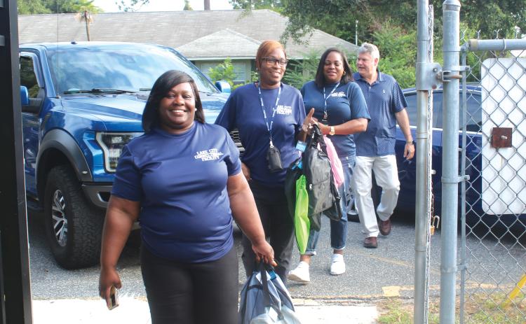 Lake City Correctional Facility employees Sonical Mitchell (from left), Twylah Queen, Deanna Lumpkin and James Deal, walk through the Eastside Elementary School gates Thursday morning while carry book bags for area students. The foursome donated book bags to several local elementary schools Thursday. (TONY BRITT/Lake City Reporter)