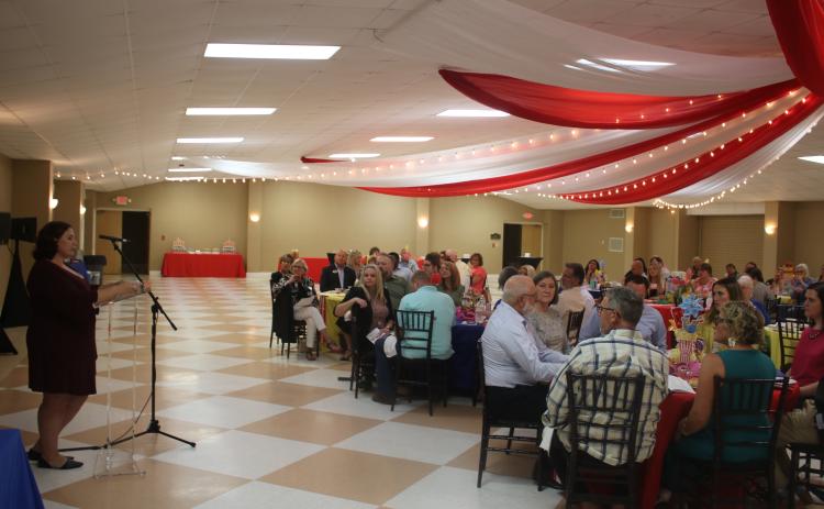 Jamie Lane (standing), a United Way of Suwannee Valley case worker, addresses the audience during the organization’s campaign kickoff Thursday night at the Florida Gateway Fairgrounds exhibition hall. (TONY BRITT/Lake City Reporter)