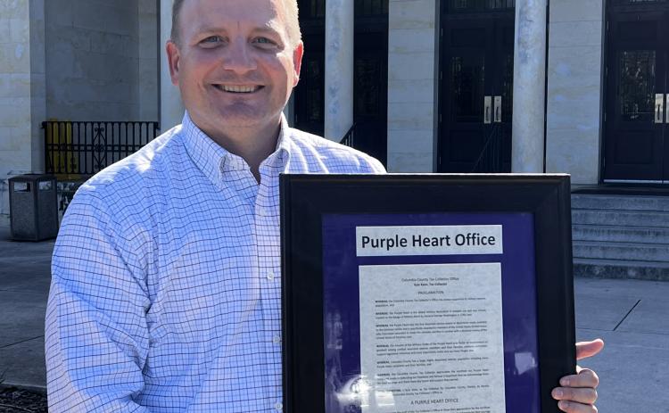 Columbia County Tax Collector Kyle Keen displays a proclamation explaining that his office has been designated as a Purple Heart Office. (COURTESY)