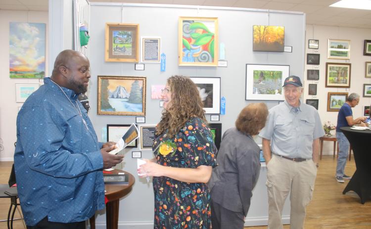 Osmund Johnson (left) shares a laugh with Sarah Stephens, the VA’s creative arts therapist, during Monday night’s veterans art exhibit award ceremony at the Gateway Art Gallery. (TONY BRITT/Lake City Reporter)