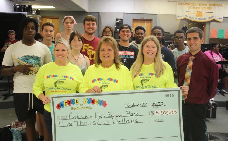 Puzzle Pieces of North Florida representatives Tabatha Feagle (from left), Kathryn Harper and Terri Prescott stand with Jay Miller, Columbia High School band director, after presenting the band with a $5,000 check on Thursday afternoon. (TONY BRITT/Lake City Reporter)