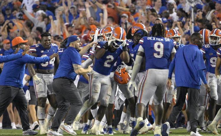 Florida linebacker Amari Burney (2) is swarmed by teammates on the sideline after making a game-saving interception in the end zone near the end of Saturday's game against Utah in Gainesville. (PHELAN M. EBENHACK/Associated Press)