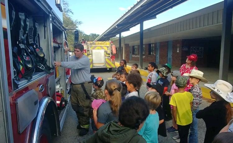 Bryan Govantes (far left), a Columbia County Fire Rescue firefighter, shows Columbia City Elementary School second grade students the equipment that firefighters use during a Fire Prevention Week presentation on Thursday morning. (TONY BRITT/Lake City Reporter)