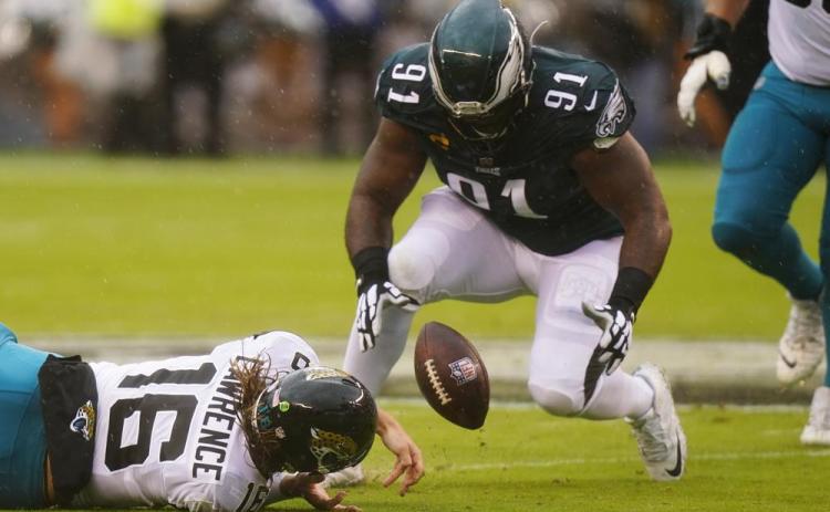 Jacksonville Jaguars quarterback Trevor Lawrence fumbles the ball and Philadelphia Eagles defensive lineman Fletcher Cox recovers it during Sunday’s game in Philadelphia. (CHRIS SZAGOLA/Associated Press)