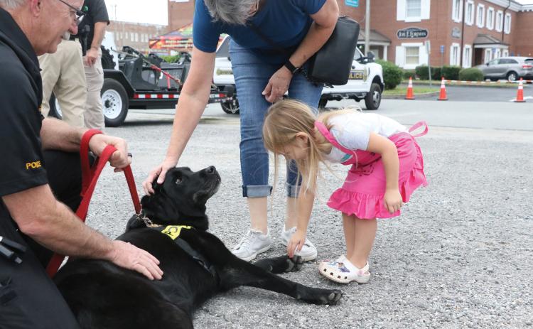 Maddie Boone (right) goes in for a pet on Fresca, an accelerant detection K9 that helps investigate cases of arson, during last year’s National Night Out event. (FILE)