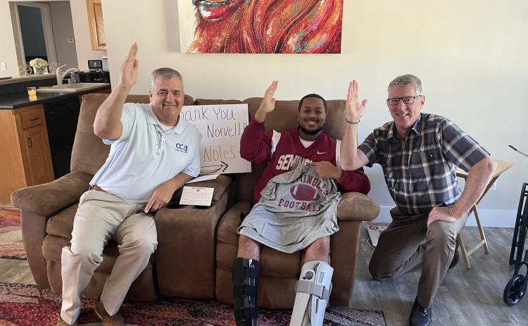 Columbia Schools Superintendent Lex Carswell (from left), Ricky Jernigan Jr. and CCS Assistant Superintendent  Todd Widergren give a tomahawk chop at Jernigan’s house after Jernigan received a letter and gifts from Florida State University football coach Mike Norvell. (COURTESY)