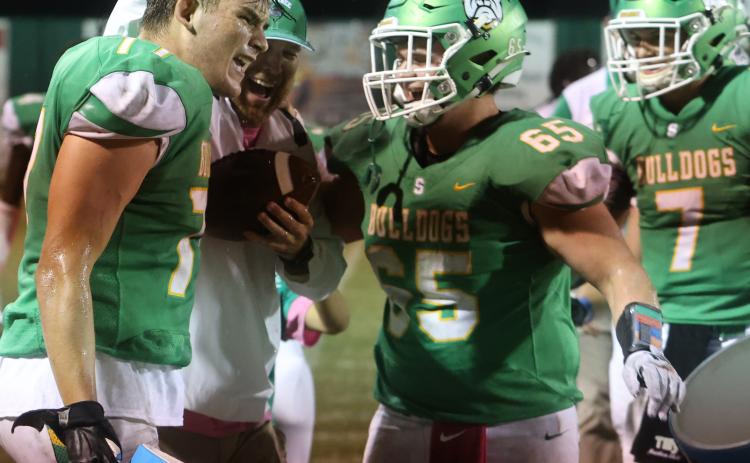 Suwannee head coach Kyler Hall laughs with offensive lineman Taylon Jones (left) and offensive lineman Andrew Harrell (right) after the team gave Hall a cooler bath following the Bulldogs’ 36-7 win over Madison County on Friday. (PAUL BUCHANAN/Special to the Reporter)