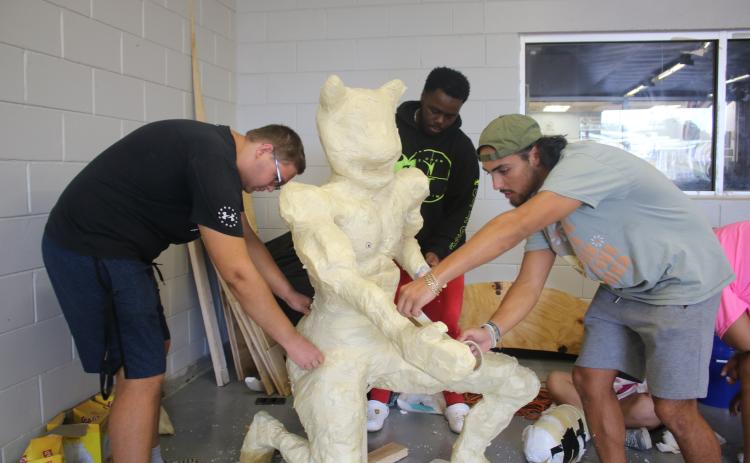 Dominic Cuadras (foreground) adds tape to a float prop as he, Ethan Pittman (left) and Xavier Combs work on the senior class homecoming float. (TONY BRITT/Lake City Reporter)