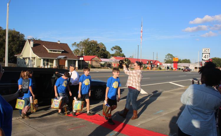 Brandon Ruwe (foreground) is greeted by Sarah Ripple, an Eastside Elementary School third-grade teacher, as he and Andrew Howard, Ryan McDaniel, Kendalynn Coates and Chloe Felton exit a limousine before Tuesday evening’s school board meeting. (TONY BRITT/Lake City Reporter)