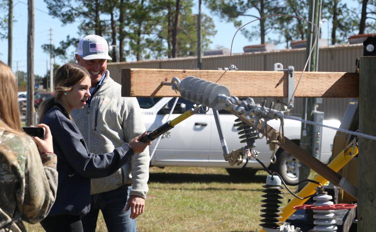 Mackenzie Thomas, a Columbia High School sophomore, learns the proper technique for handling electrical equipment at the Clay Electric Cooperative booth Wednesday morning. (MORGAN MCMULLEN/Lake City Reporter)