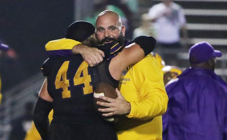 Columbia defensive coordinator John Woodley hugs defensive tackle Caden Bolstein (44) after Columbia stopped Choctaw on fourth down in overtime of Friday’s Region 1-3S final. (BRENT KUYKENDALL/Lake City Reporter)