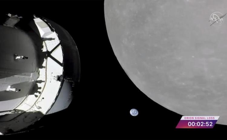 This screengrab from NASA TV shows NASA’s Orion capsule, left, nearing the moon Monday. At center is earth. (NASA via AP)