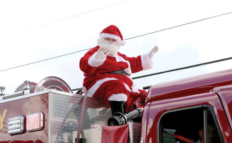 Santa Claus waves atop a firetruck during last year’s Fort White Christmas parade. (FILE)