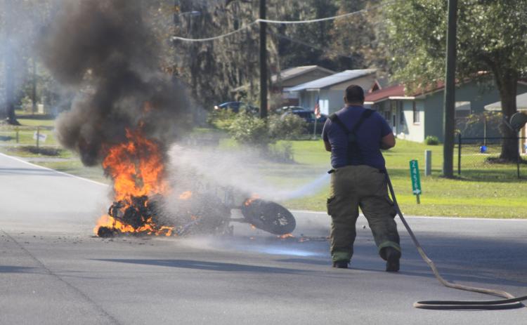 A Columbia County firefighter extinguishes the flames from the motorcycle Tuesday afternoon. (MATTHEW GLOVER/Special to the Reporter)