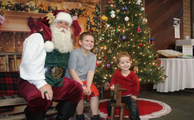 Santa Claus (from left) gets smiles from Bentley Strickland, 9, and Carleigh Holeman, 3, during an after-hours event at the Columbia County Public Library that was attended by more the 25 children. (TONY BRITT/Lake City Reporter)