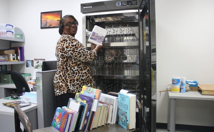 Mary Williams, the manager of the West Branch Library, places books in a book sanitizer. Williams, who has been an employee in the Columbia County Public Library System, is planning to retire in a few days after working as a librarian for 42 years. A drop-in retirement reception for her will take place from 4:30-6 p.m. Monday at the Main Library. (TONY BRITT/Lake City Reporter)