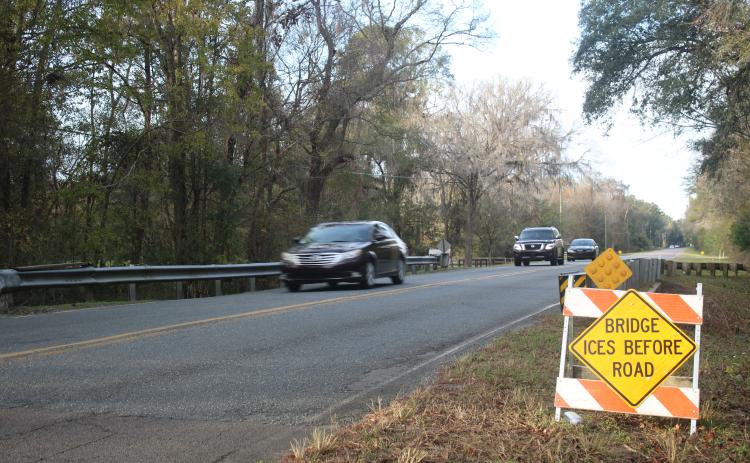 Vehicles travel southbound on Southeast Country Club Road on Thursday afternoon, after county crews erected hazardous conditions signs for both lanes of travel for a local bridge. The signs have been erected at 34 locations across the county. (TONY BRITT/Lake City Reporter)