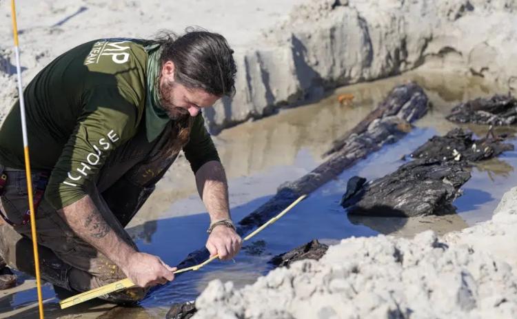 Archaeologist Christopher McCarron takes measurements of a structure exposed in the sand Tuesday in Daytona Beach Shores. (JOHN RAOUX/Associated Press)