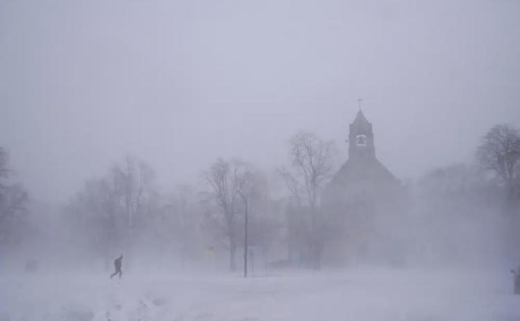 A lone pedestrian in snow shoes makes his way across Colonial Circle as St. John’s Grace Episcopal Church rises above the blowing snow amid blizzard conditions in Buffalo, N.Y., on Saturday. (DEREK GEE/The Buffalo News via AP)