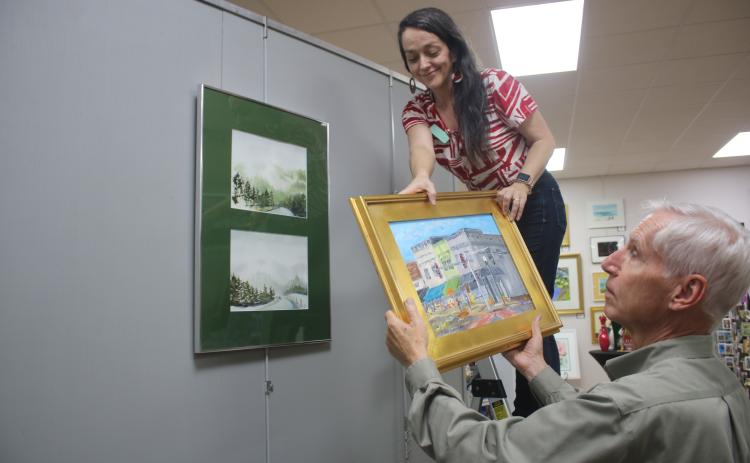 Sheila Carr, Gateway Art Gallery Curator, is assisted by Jim Riley as she hangs artwork for the upcoming ‘The Art Of Matter’ exhibit which will be featured in the gallery during January. (TONY BRITT/Lake City Reporter)