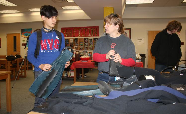 Logan Wilson (left), a Fort White High School sophomore listens to Jackie Clark, a FWHS English teacher, as she shows off some of her cave diving equipment on Friday. (TONY BRITT/Lake City Reporter)
