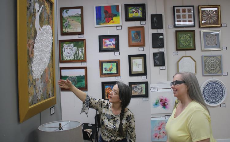Gateway Art Gallery Curator Sheila Carr (left) points out a work of 3D art to Melanie Thum. (TONY BRITT/Lake City Reporter)