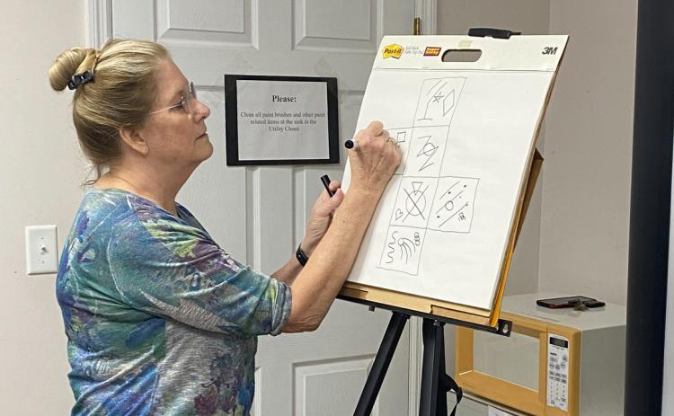 Laura Hunter-Null draws on a canvas during an ‘Altrusa Kids’ lesson to help local children achieve literacy. (COURTESY)