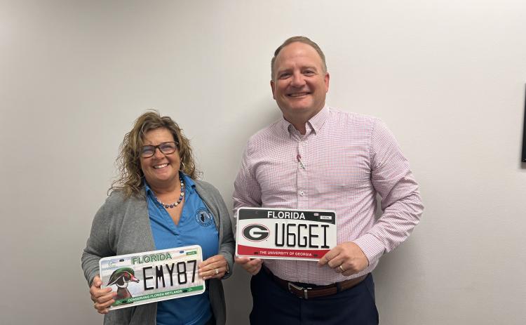 Columbia County Tax Collector Kyle Keen (right) holds the new University of Georgia license plate while Tracy Nettles, the director of motor services at the tax collector’s office, holds the Ducks Unlimited plate. (JAMIE WACHTER/Lake City Reporter)