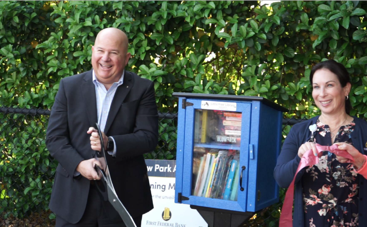 John Medina, president and CEO of First Federal Bank, cuts the ribbon on a Little Free Library at the Kiwanis Children’s Park adjacent to the bank’s headquarters on W. U.S. Highway 90 during a ceremony Thursday morning. Also pictured is Stephanie Esposito, the bank’s corporate marketing manager. (COURTESY)