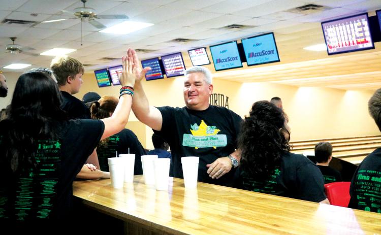 Jesse Stalnaker (right) gives out a high-five during the eighth annual Fins and Pins Bowl-a-Thon in 2019. (FILE)