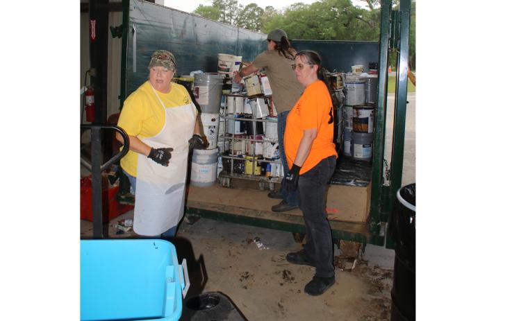 Pam Davis, Winfield Solid Waste director (clockwise from left), and solid waste facility employees Heather Crowder and Robyn Fussnecker place cans of paint into a dumpster during Saturday’s Toxic Roundup. (TONY BRITT/Lake City Reporter)