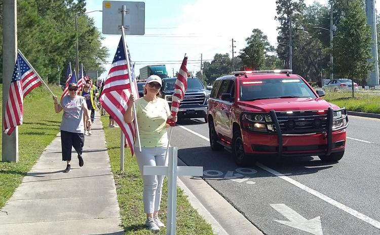 Volunteers, with assistance from the Lake City Fire Department, erect the crosses and flags alongside State Road 47 Saturday morning for the America’s Heroes Program. (COURTESY)