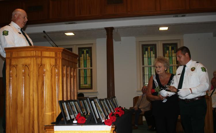 Mollie Burch, the mother of fallen Florida Forest Service Ranger Josh Burch, was escorted by Forest Ranger Ryan Rehberg to place a rose in honor of her son during Tuesday’s Public Safety Memorial service at First Baptist Church. (TONY BRITT/Lake City Reporter)