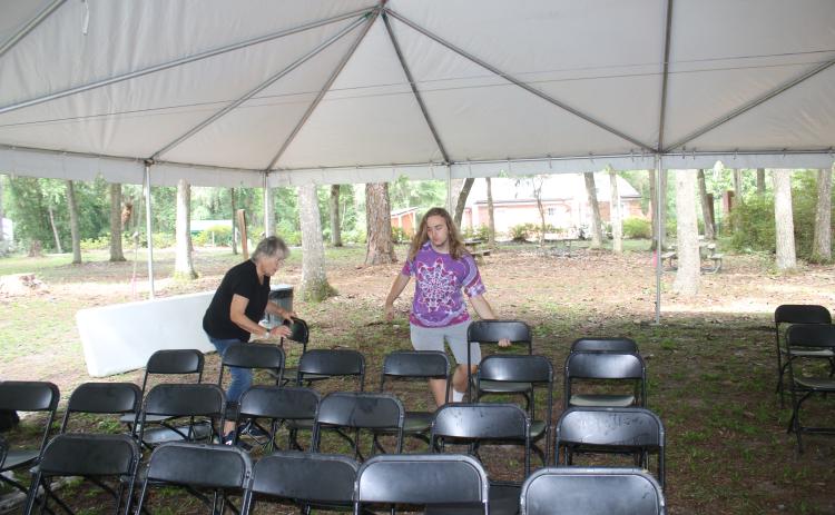 Volunteers Joan Alderman (left) and David Enfinger set up chairs beneath a tent at one of the stages for the Florida Folk Festival on Wednesday. (TONY BRITT/Lake City Reporter)