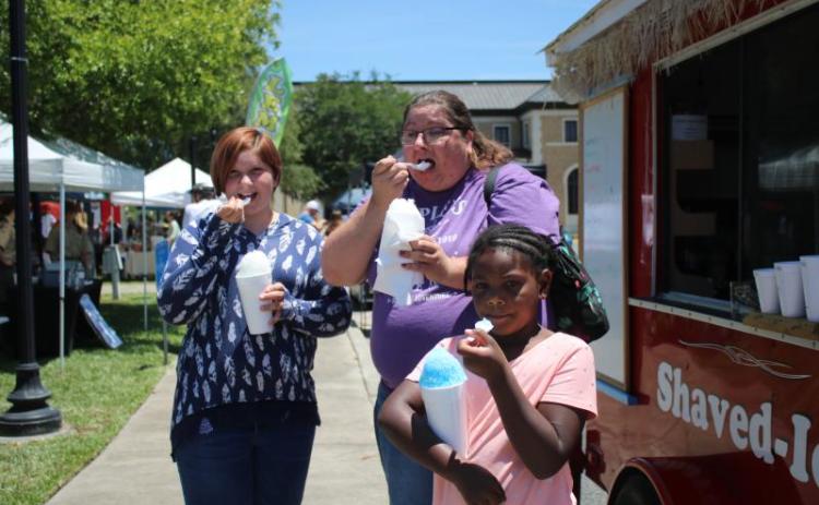 Hannah Hunter (from left), Jessica Frame and Kaleah Shead enjoy their cups of shaved ice while attending the Spring Market in Olustee Park in May 2021. (FILE)