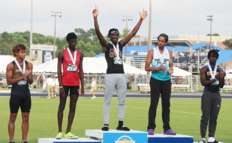 Columbia’s Seth Stockton celebrates on the podium after winning the class 3A state title in the triple jump on Friday. (COURTESY)