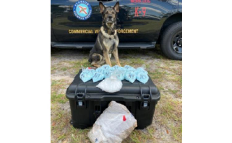A Florida Highway Patrol K-9 officer in front of drugs confiscated during a multi-jurisdictional strike force operation in Columbia County last week. (COURTESY)